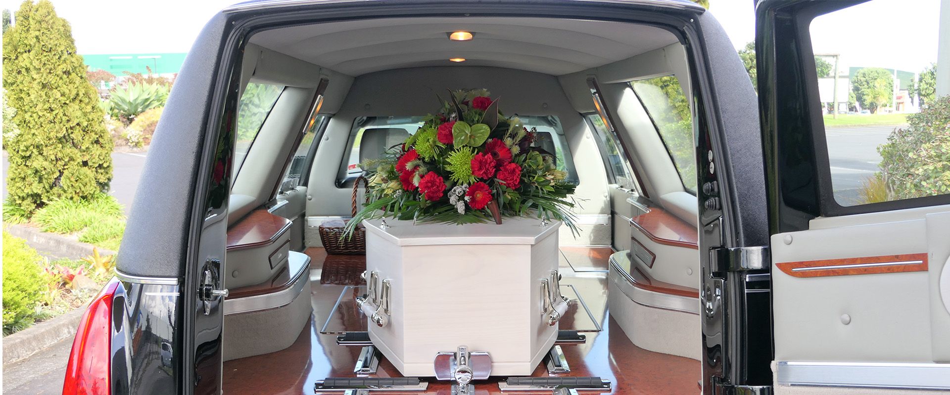 Ein Bestattungsauto mit einen Sarg der mit Blumen geschmückt ist.